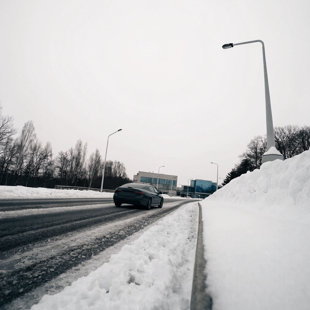 Автомобиль едет по заснеженной дороге за городом